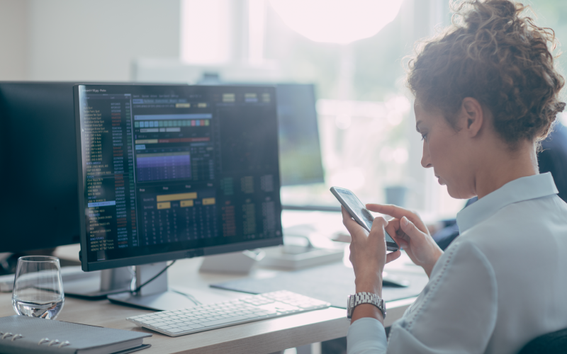 woman reading management steps on phone whilst at computer